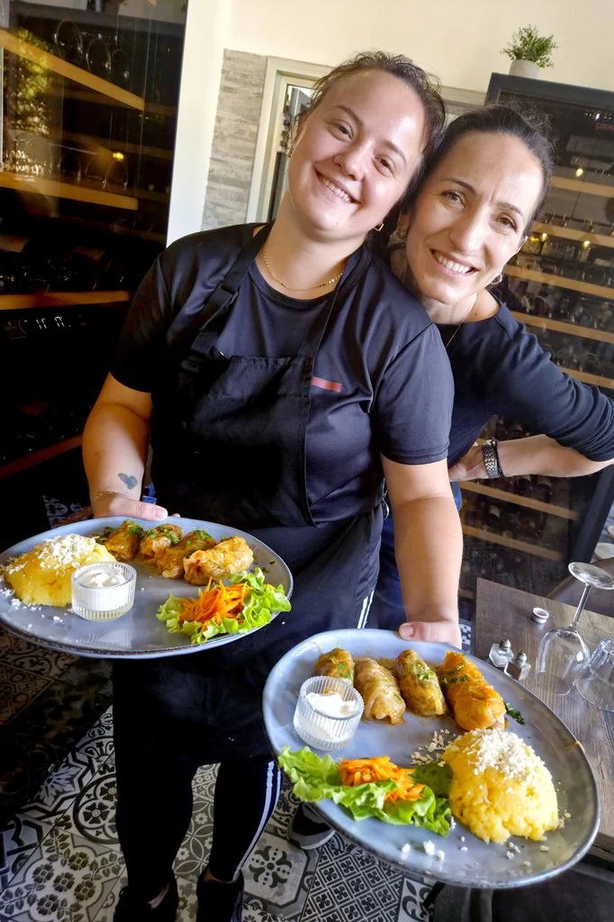Deux membres de l’équipe souriantes présentent les plats du restaurant